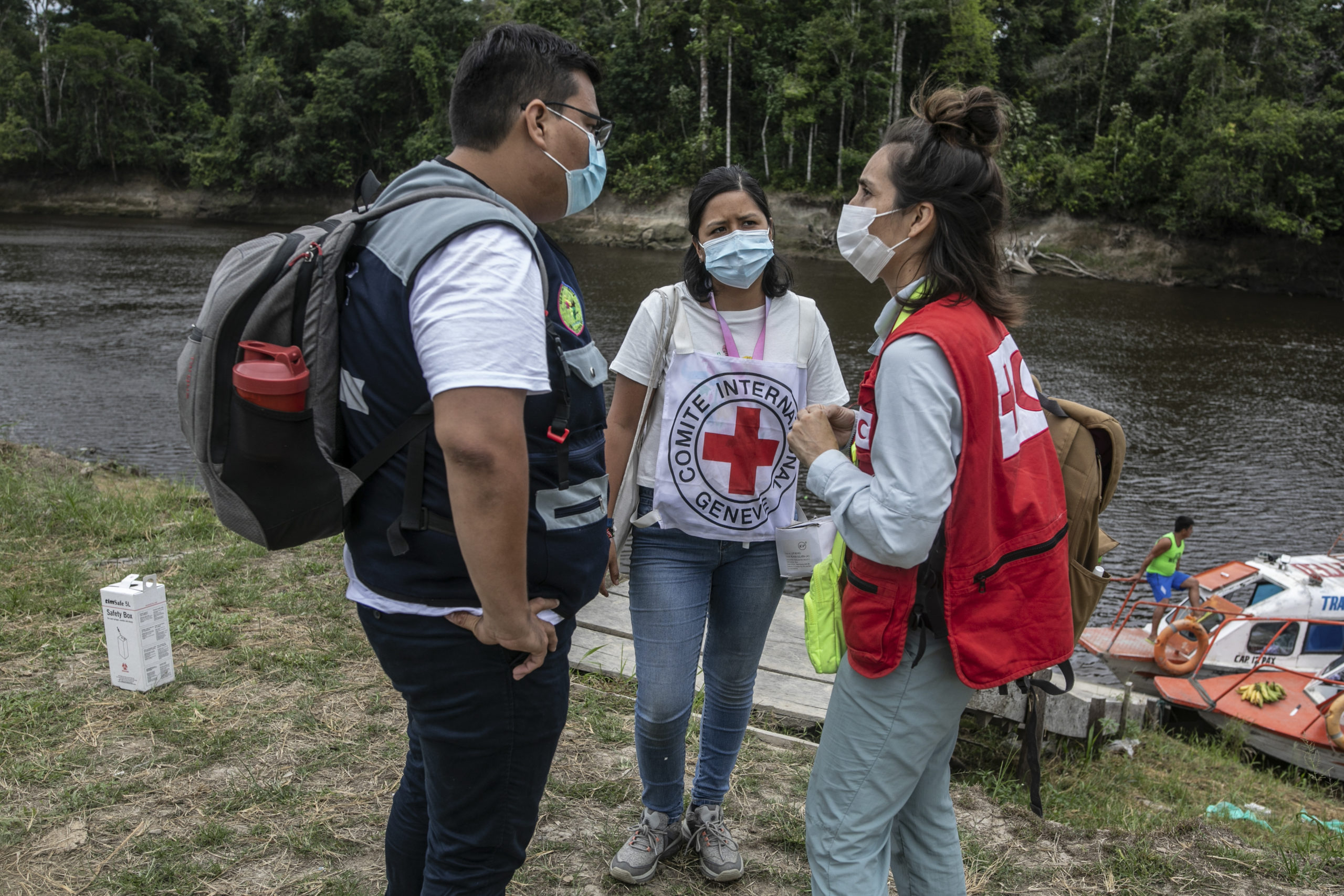 Two ICRC and IFRC Staff are talking to a man.