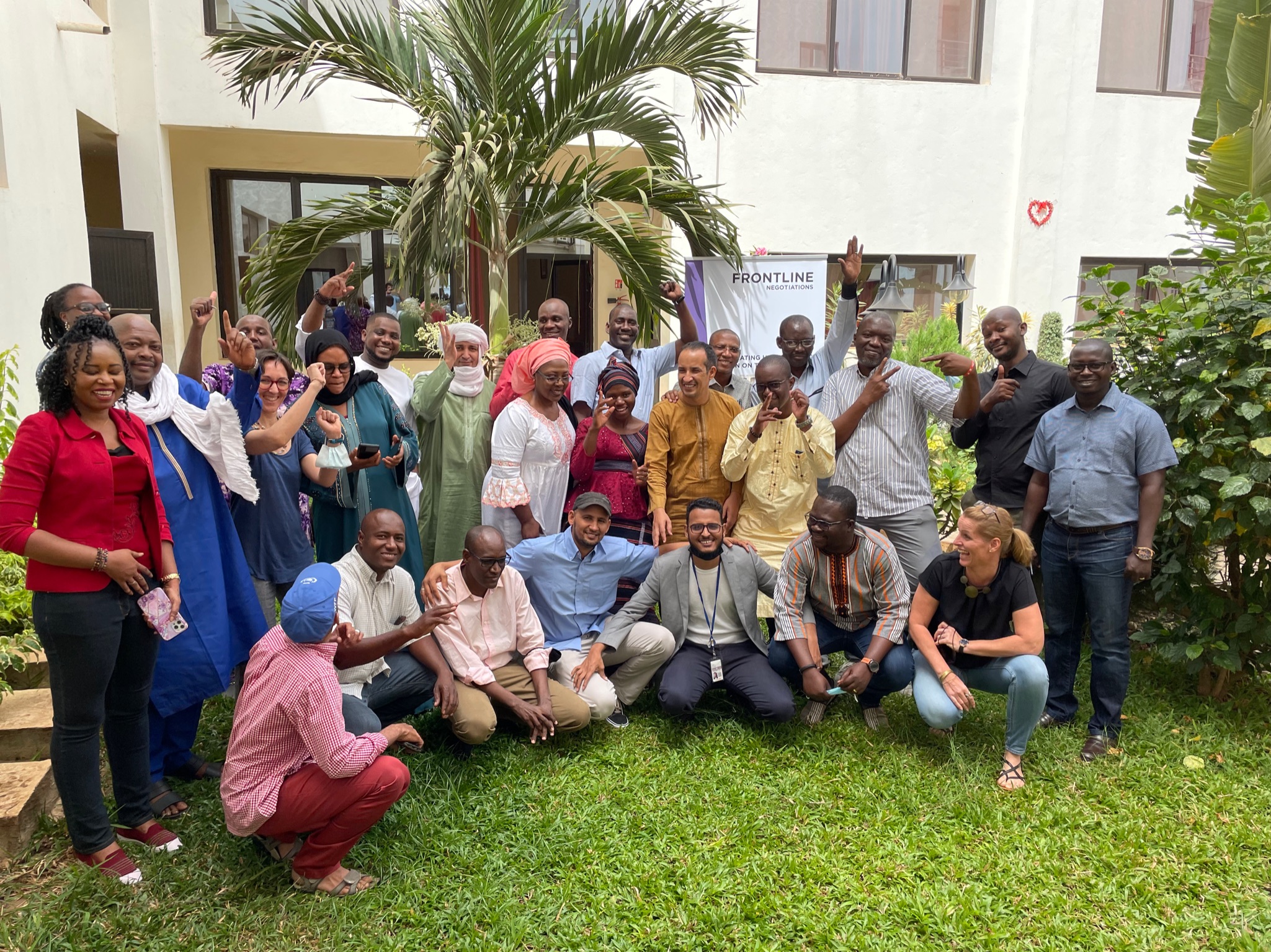 Profesionales del sector humanitario que trabajan en la región del Sahel en el exterior de un edificio para una foto de grupo. Están ayudando a sus colegas a desarrollar su competencias de negociación a través de talleres.